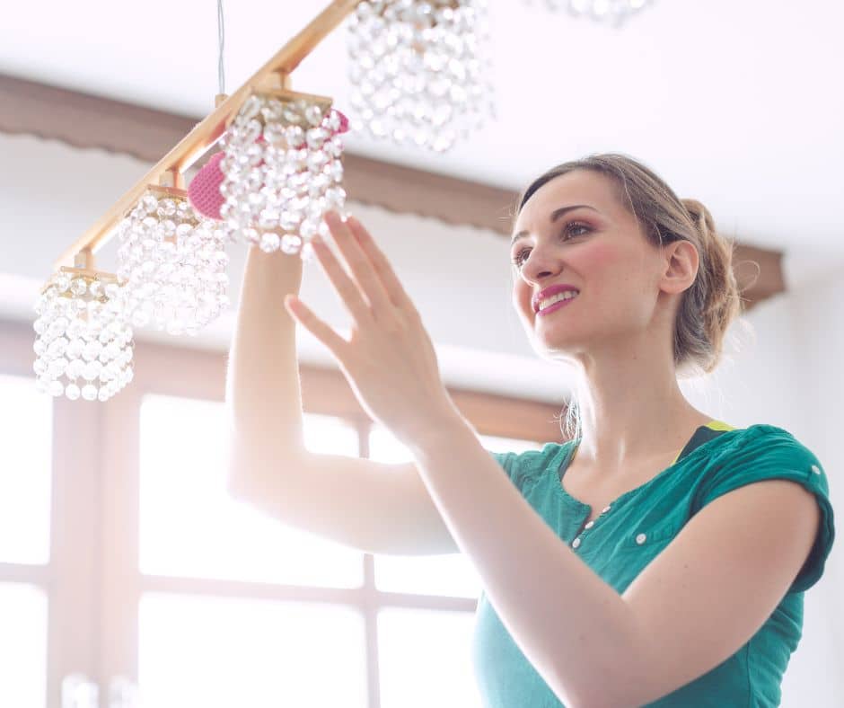 A woman spring cleaning a chandelier.
