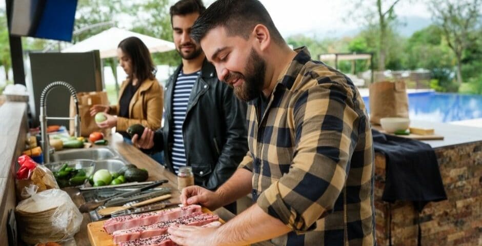 Outdoor kitchens- men grilling steaks and enjoying the outdoor kitchen